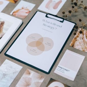 Flat lay of brand strategy clipboard with Pantone cards and aesthetic images on desk.
