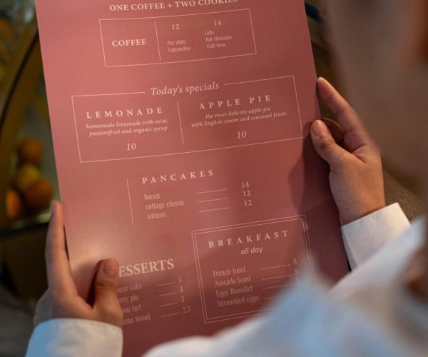 A person holding a menu from Rosie's Coffee showing various food and beverage options.