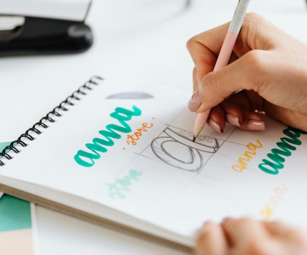 Close-up of a woman hand lettering colorful text in a notebook.